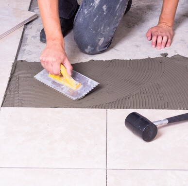 Installer applying tile adhesive for installation